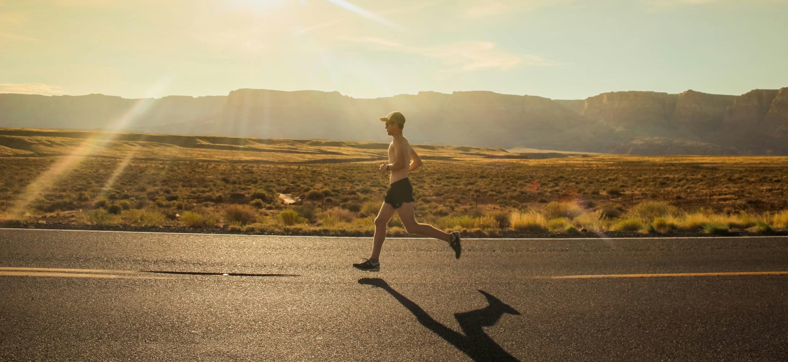 Coureur à l'entraînement sur une route, au soleil.
