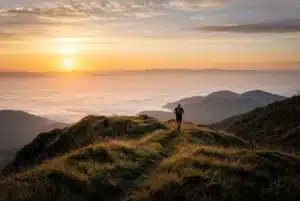 Coureur de trail sur un sentier de crête des Vosges au lever du jour, plaine d'Alsace sous la brume